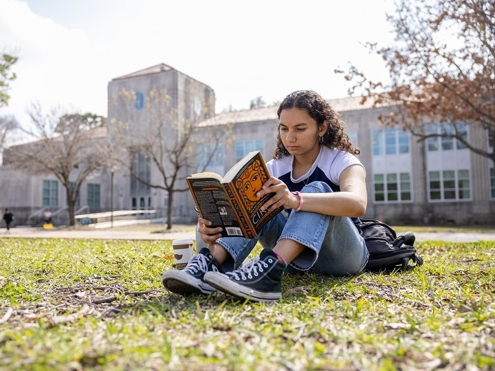 Student reading a book in Cullen Family Plaza